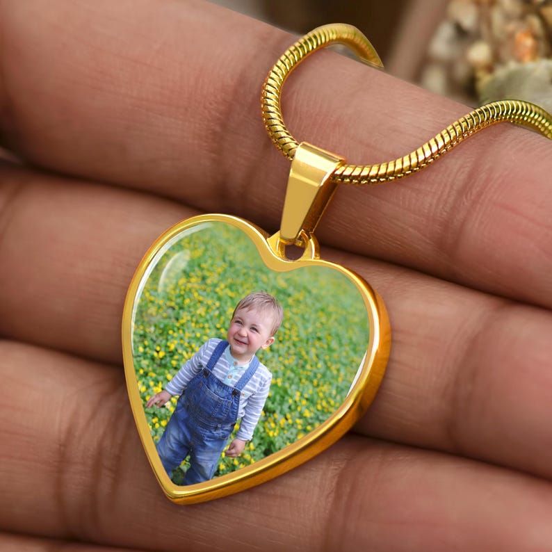 a person holding a heart shaped pendant with a picture on it