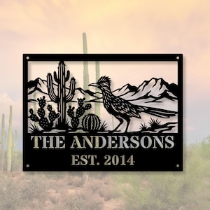 May include: Black metal sign featuring a desert scene with a roadrunner, cacti, and mountains. The sign reads "THE ANDERSONS EST. 2014" in a decorative font. The sign has a rectangular frame with mounting holes in each corner.