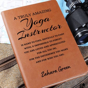 May include: A brown leather journal with the text "A Truly Amazing Yoga Instructor" and a quote about being hard to find, difficult to part with, and impossible to forget. The journal is personalized with the name "Zahara Green".
