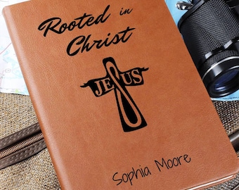 May include: Brown leather journal with the text "Rooted in Christ" and a cross with the word "Jesus" on it. The name "Sophia Moore" is engraved at the bottom.