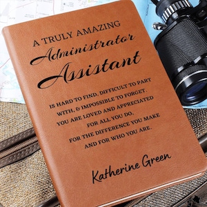 May include: A brown leather-bound journal with the text "A Truly Amazing Administrator Assistant is hard to find, difficult to part with, & impossible to forget. You are loved and appreciated for all you do, for the difference you make and for who you are." and the name "Katherine Green" printed on the cover.