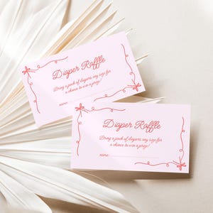 May include: Two pink cards with red text and a red ribbon design. The text on the cards reads "Diaper Raffle" and "Bring a pack of diapers any size for a chance to win a prize!"
