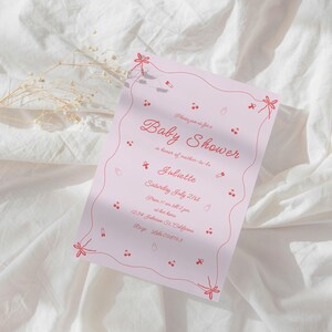 May include: Pink baby shower invitation with red floral accents and the text "Baby Shower" in cursive. The invitation is for Juliette and is set for Saturday, July 21st at 1 p.m. at the host's home. The address is 1234 Delicious Dr. California. RSVP by July 15th.