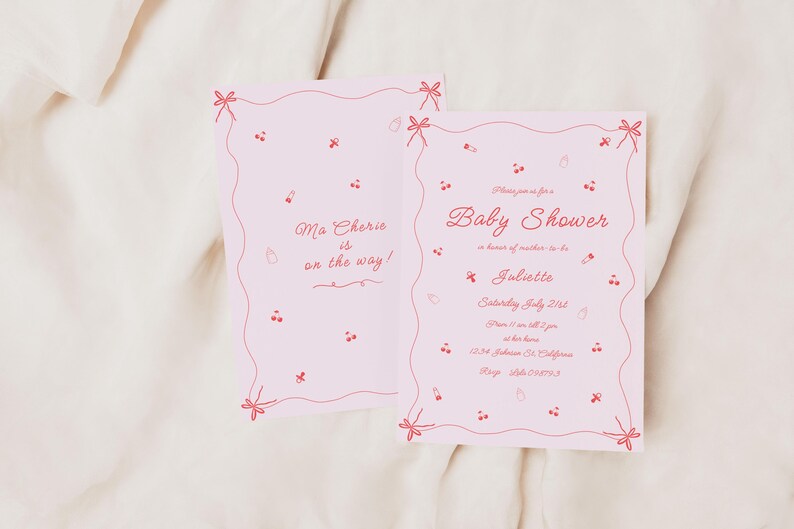 May include: Pink baby shower invitation with a red border and red illustrations of cherries and bows. The text reads "Please join us for a Baby Shower in honor of mother-to-be Juliette. Saturday, July 21st. 2-5 pm at her home. 1234 Johnson St. California. RSVP 555-123-4567."