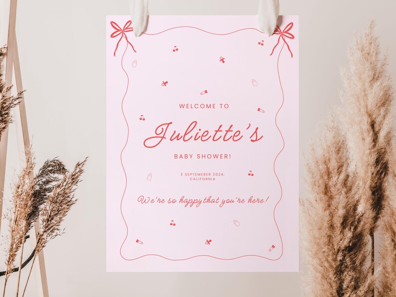 May include: A pink welcome sign with a wavy border and red text that reads "Welcome to Juliette's Baby Shower! September 2024, California. We're so happy that you're here!"