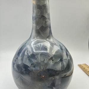 May include: A blue and gold ceramic vase with a round body and a long neck. The vase has a floral pattern.