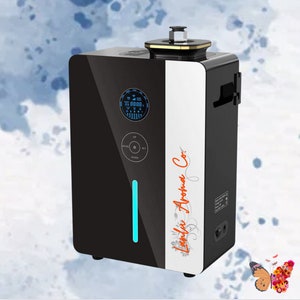 Puede incluir: Un difusor de aceites esenciales negro y blanco con una pantalla digital y una luz azul. El difusor tiene un panel blanco con el texto "Luxury Aroma Co." en naranja.