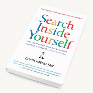 May include: A white book with a colourful title "Search Inside Yourself" by Chade-Meng Tan. The book cover features a small illustration of a person sitting in a meditative pose. The subtitle reads "The Unexpected Path to Achieving Success, Happiness (and World Peace)".