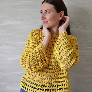 May include: A yellow crochet top with a loose, open-weave design. The top has long sleeves and a round neckline.