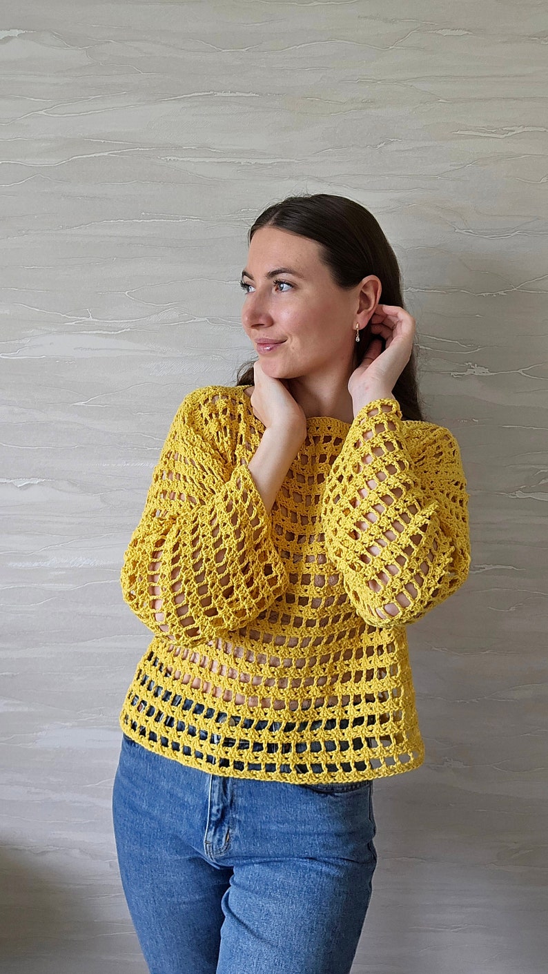 May include: A yellow crochet top with a loose, open-weave design. The top has long sleeves and a round neckline.