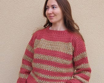 May include: A striped sweater with a red and gold color scheme. The sweater has a round neckline and long sleeves.