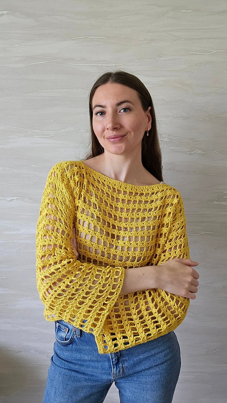 May include: A yellow crochet top with a loose fit and bell sleeves. The top has a square-shaped open stitch pattern.