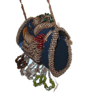 May include: A beaded purse with a blue fabric base and a variety of colored beads, including clear, silver, red, green, and gold. The purse has a fringe of beads and is decorated with a floral design.