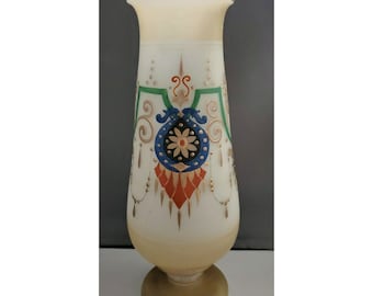 May include: A tall, cream-colored glass vase with a wide base and a flared top. The vase is decorated with colorful floral and geometric designs in blue, green, orange, and gold. The vase is approximately 10 inches tall.