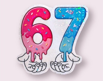 May include: A glittery sticker featuring the number 67, designed to resemble donuts. The number 6 is pink with sprinkles, and the number 7 is blue with sprinkles. The numbers appear to be dripping and are held by cartoon hands.