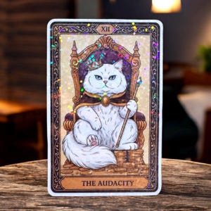May include: A tarot card featuring a white cat wearing a crown and cape, seated on a throne. The cat holds a scepter and sits atop a pile of gold coins. The card is framed with ornate borders and the text "THE AUDACITY".