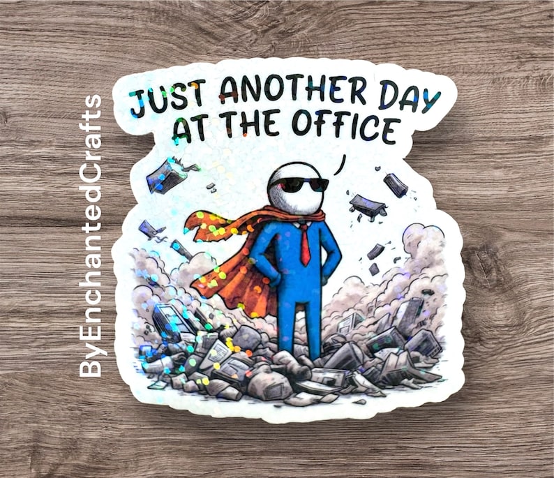 A rectangular vinyl sticker featuring a minimalist, retro-inspired design. The text reads "Just Another Day At The Office" in a bold, vintage-style serif font. Below the text is a simple line-art illustration of a traditional office building with a small flag on top. The sticker has a clean, white background with a thin black border, perfect for laptop or water bottle decoration.