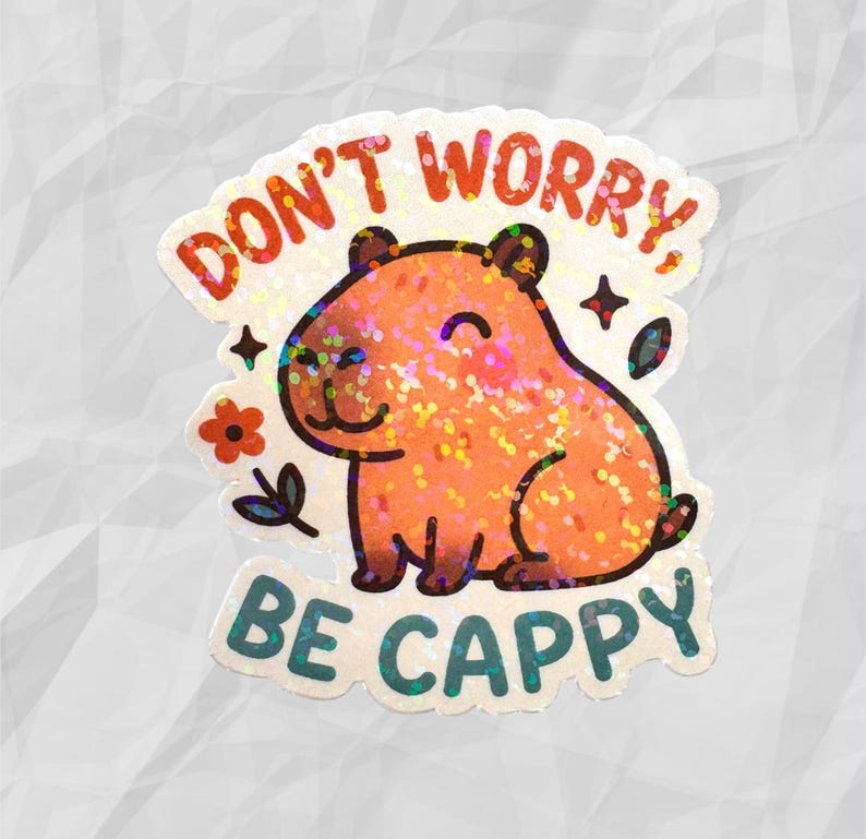 This sticker features an adorable, cartoon-style capybara sitting contentedly with a big, peaceful smile and closed eyes. The capybara has a light brown body with darker brown accents for the ears, outline, and tiny fur markings.  Above the capybara, the text reads “DON’T WORRY,” in playful, rounded orange letters. Below the capybara, the phrase “BE CAPPY” is written in bold, teal-blue bubble letters — a clever pun combining “happy” and “capybara.”