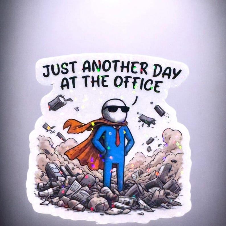 A rectangular vinyl sticker featuring a minimalist, retro-inspired design. The text reads "Just Another Day At The Office" in a bold, vintage-style serif font. Below the text is a simple line-art illustration of a traditional office building with a small flag on top. The sticker has a clean, white background with a thin black border, perfect for laptop or water bottle decoration.