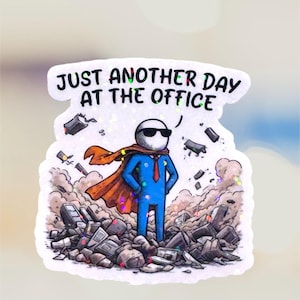 A rectangular vinyl sticker featuring a minimalist, retro-inspired design. The text reads "Just Another Day At The Office" in a bold, vintage-style serif font. Below the text is a simple line-art illustration of a traditional office building with a small flag on top. The sticker has a clean, white background with a thin black border, perfect for laptop or water bottle decoration.