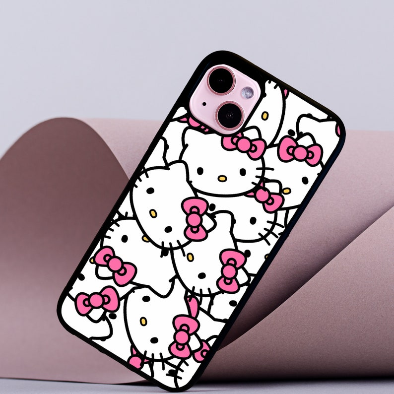 May include: Black phone case with a white background and a pattern of pink Hello Kitty characters.