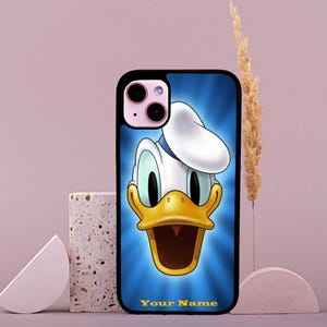 Peut inclure: Une coque de téléphone noire avec une image de dessin animé de Donald Duck. L'arrière-plan est bleu avec un chapeau de marin bleu clair et blanc sur la tête de Donald Duck. Le texte "Your Name" est en bas de la coque.