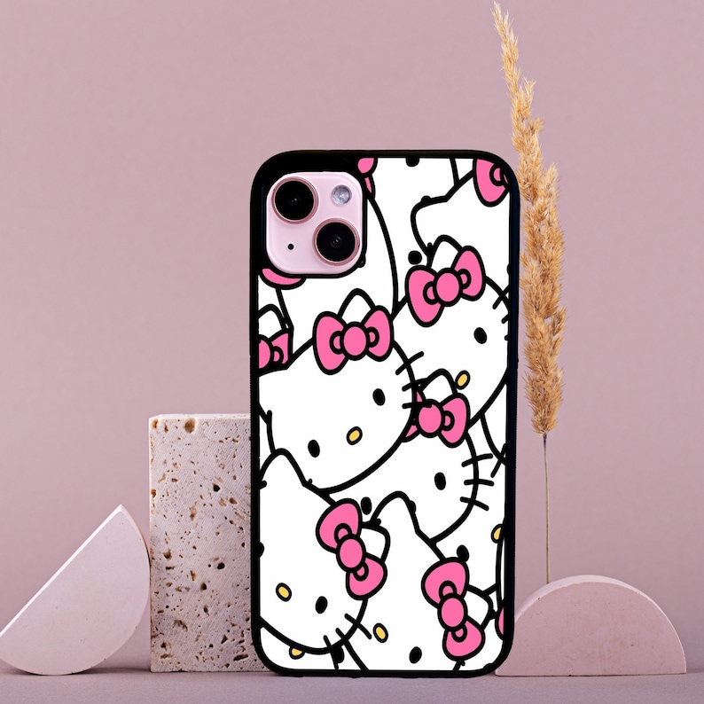 May include: Black phone case with a white background and a repeating pattern of Hello Kitty characters with pink bows.