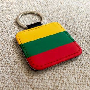 Puede incluir: Llavero cuadrado con la bandera de Lituania. El llavero tiene un diseño amarillo, verde y rojo, con un llavero plateado y una correa negra. Los bordes están cosidos con hilo rojo.