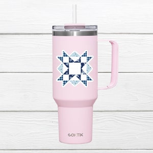May include: A light pink insulated tumbler with a handle and a straw. The tumbler features a sticker with a blue and white quilt block design. The brand name "OKTIK" is printed at the bottom of the tumbler.