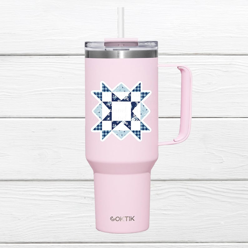 May include: A light pink insulated tumbler with a handle and a straw. The tumbler features a sticker with a blue and white quilt block design. The brand name "OKTIK" is printed at the bottom of the tumbler.