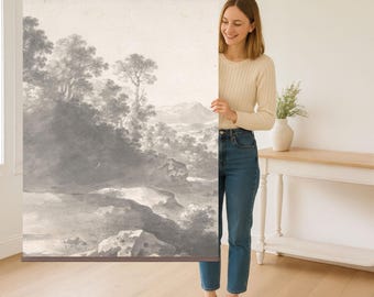 May include: A black and white landscape print of a river flowing through a valley with trees and hills. The print is on a canvas and is being held by a person.