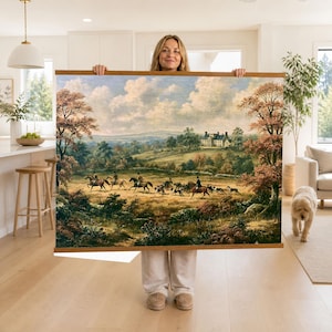 May include: A large rectangular wall hanging featuring a landscape painting of a fox hunt. The scene depicts riders on horseback and hounds in a grassy field with trees, rolling hills, and a large house in the distance, framed by wooden rails.