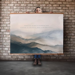 May include: A framed art print featuring a watercolor landscape of layered mountains in shades of blue, gray, and beige. The print includes the text "WHEN MY HEART IS OVERWHELMED, LEAD ME TO THE ROCK THAT IS HIGHER THAN I - PSALM 61:2."