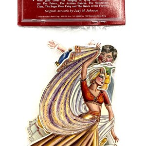 May include: Set of six die-cut paper decorations featuring characters from the Nutcracker ballet. The characters include the Arabian Dancer, the Sugar Plum Fairy, and the Prince. The decorations are gold-stamped and have gold cords for hanging.