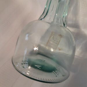 Op de afbeelding: Een heldere glazen fles met een getextureerd oppervlak en een etiket met de tekst "Vetreria Etrusca".