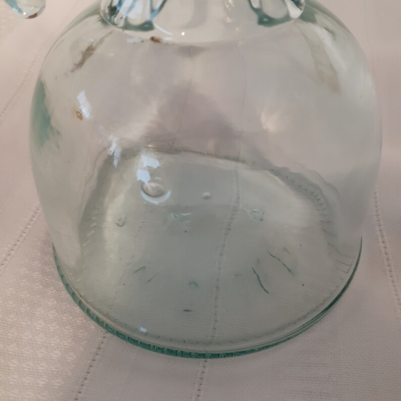 Op de afbeelding: Een heldere glazen fles met een getextureerd oppervlak. De fles heeft een brede opening en een afgeronde bodem. De fles is leeg.