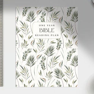 May include: A white planner with a green leafy pattern and the text "One Year Bible Reading Plan".