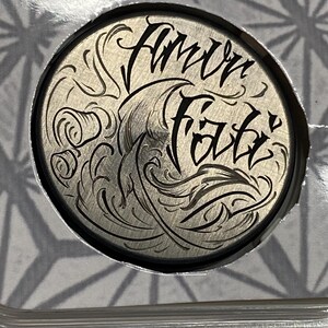 May include: A silver round metal disc with a black engraved design. The design features a wave with a stylized inscription that reads "Full Faith".