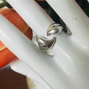 May include: A silver ring with two teardrop-shaped pieces that are connected together.