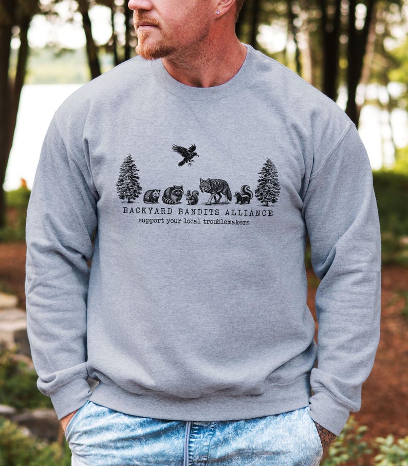 May include: A gray sweatshirt with a black graphic print of a forest scene with animals and the text "Backyard Bandits Alliance support your local troublemakers".