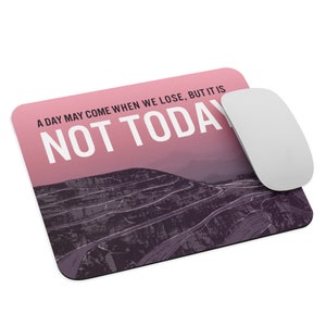 Könnte beinhalten: Rechteckiges Mauspad mit einem rosa-violetten Berglandschaftsdesign. Der Text "A DAY MAY COME WHEN WE LOSE, BUT IT IS NOT TODAY" ist in Weiß aufgedruckt. Eine weiße kabellose Maus liegt rechts auf dem Pad.