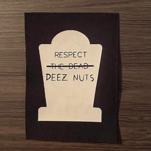 May include: Black rectangular patch with a white tombstone design. The tombstone has the words "RESPECT THE DEAD" with "THE DEAD" crossed out and "DEEZ NUTS" below. The patch is likely for clothing or accessories.
