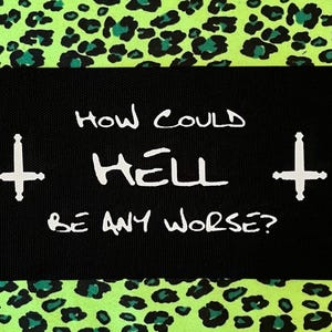 May include: A rectangular black fabric patch featuring the white text "HOW COULD HELL BE ANY WORSE?" flanked by two white inverted cross symbols. The patch is set against a vibrant neon green background with a black and dark teal leopard print pattern.