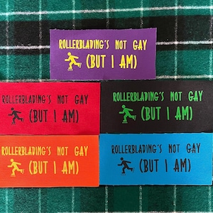 May include: Five rectangular fabric patches in purple, red, black, orange, and blue. Each patch features the text "ROLLERBLADING'S NOT GAY (BUT I AM)" in a contrasting color, accompanied by a small graphic of a person on rollerblades.