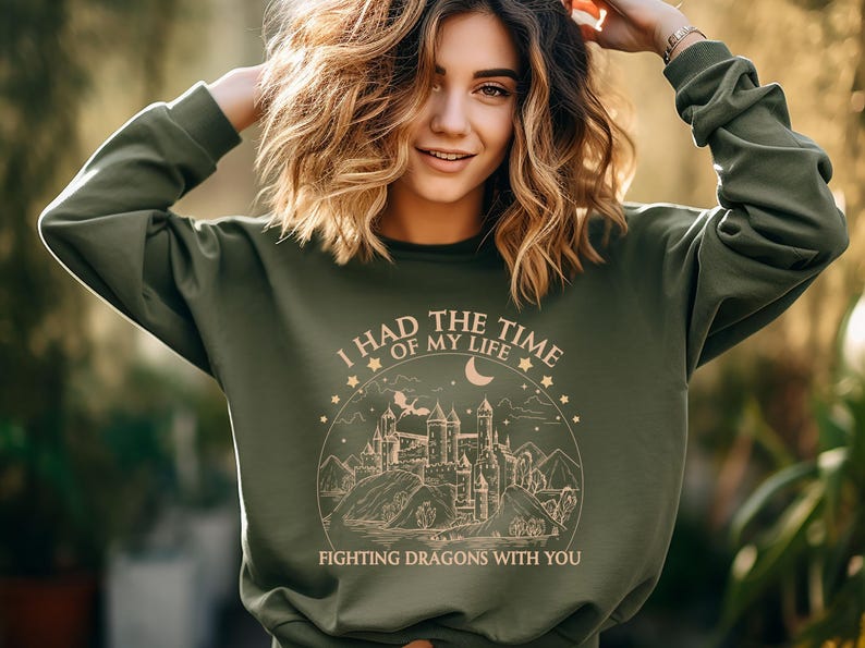 Op de afbeelding: Groen sweatshirt met een grafische print van een kasteel, maan en sterren. De tekst luidt "Ik had de tijd van mijn leven om draken met je te bevechten."