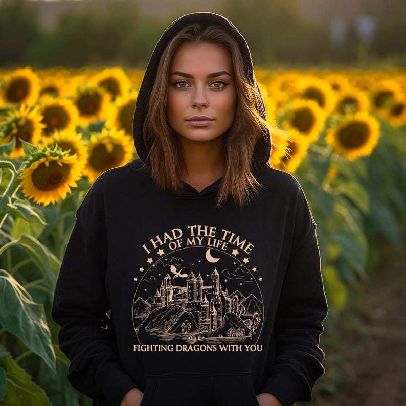 Op de afbeelding: Zwarte hoodie met een gouden grafische print van een kasteel en de tekst "Ik had de tijd van mijn leven om draken met je te bevechten".