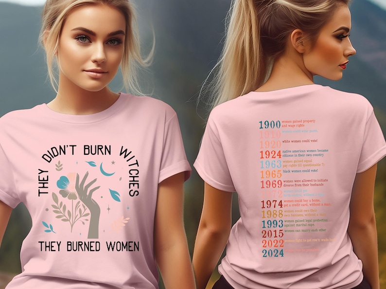 May include: Pale pink t-shirt featuring the slogan "THEY DIDN'T BURN WITCHES THEY BURNED WOMEN" with a hand and floral graphic. The back of the tee lists women's rights milestones from 1900 to 2024.