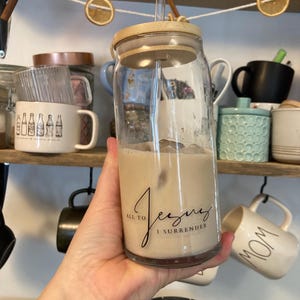 Könnte beinhalten: Ein Set aus drei Keramikbechern mit gesprenkelter, matter Oberfläche. Die Becher sind in den Farbtönen Creme, Hellgrau und Dunkelgrau gehalten. Jeder Becher hat ein schlichtes, minimalistisches Design und einen abgerundeten Henkel.