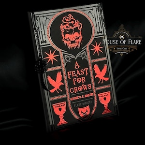May include: A black book cover with red and silver accents. The title "A Feast for Crows" is displayed with a skull and crow imagery. The author's name, George R.R. Martin, is also visible. The book has a decorative chain.