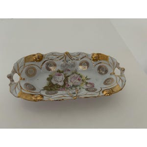 May include: A white ceramic mug with a black handle and the text "But First, Coffee" in a black, bold font. The mug is on a white surface.